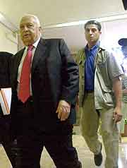 Den israelske statsministeren Ariel Sharon blir anbefalt å finne seg livvakter som ikke ser så strenge ut som mannen bak han. (Foto:NRK)