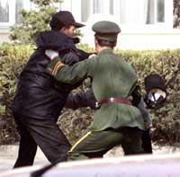 En kinesisk soldat prøver å stoppe en av nordkoreanerne i det han og 24 andre stormet den spanske ambassaden. (Foto: AP)