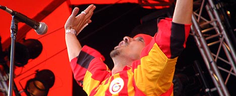 Manu Chao, kledd i rødgul fotballgenser, kaptein for det tallrike bandet (foto: Jørn Gjersøe). Manu Chao, kledd i rødgul fotballgenser, kaptein for det tallrike bandet (foto: Jørn Gjersøe).