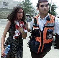 En skadd kvinne hjelpes ut av kafeterian ved universitetet i Jerusalem onsdag 31. juli 2002. (Foto: Reuters/Nir Elias)