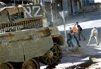 Palestinsk ungdom kaster stein mot israelsk stridsvogn. (Arkivfoto: Reuters/Scanpix)