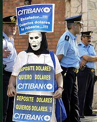 En maskert demonstrant holder opp en plakat hvor det står skrevet "Jeg satte inn dollar, jeg vil ha ut dollar" foran presidentpalasset i Buenos Aires 18. november 2002. (Foto: Reuters/Enrique Marcarian)