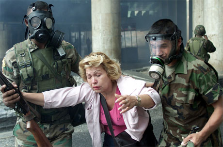En kvinnelig bankansatt blir hjulpet i sikkerhet av soldater. (Foto: Chico Sancez, Reuters)