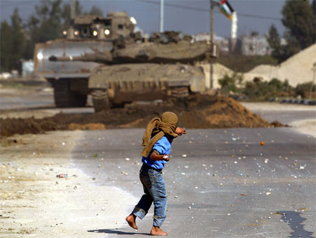 En palestinsk 11-åring kaster stein mot israelske soldater under en israelsk militæraksjon på Gazastripen. (Foto: Reuters/Scanpix)