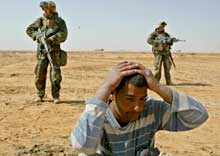 I SIVIL: De amerikanske marineinfanteristene ser seg vaktsomt omkring mens en irakisk mann de tror kan være soldat, kneler på bakken (Foto: Oleg Popov/Reuters).