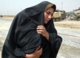 Irakisk flyktning fra Bagdad prøver å beskytte barnet sitt mot heten på landeveien (REUTERS/Oleg Popov)