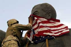 En amerikansk marinesoldat danderer et amerikansk flagg rundt hodet til Saddam-statuen. Foto: Reuters/Goran Tomasevic.