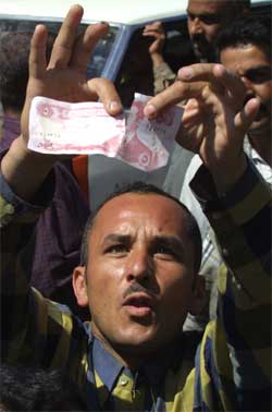 En iraker river i stykker en dinar-seddel med Saddams portrett i Mosul. (Foto: Reuters/Caren Firouz)