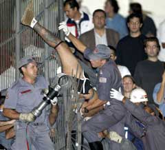 Brasiliansk politi hjelper en Corinthians-fans som hadde satt seg fast i gjerdet under kampen mot River Plate. (Foto: Paulo Whitaker/Reuters)