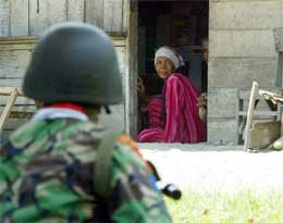 Kvinne i Aceh betrakter en indonesisk soldat etter et sammenstøt mellom hæren og separatiskbevegelsen GAM i dag (Reuters)