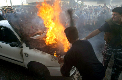Folk som kom til prøvde å sløkkje brannen i bilen til Hamas-leiaren Massoud Titi. (Foto: Suhaib Salem, Reuters)