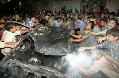 Palestinere forsøker å slukke en bil som brenner etter et israelsk rakettangrep i Gaza by fredag kveld. (Foto: Suhaib Salem/Reuters) 