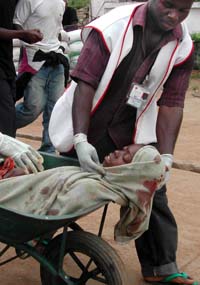 En kvinne såret av en rakett som havnet blant flyktningene i Monrovia kjøres i trillebår til sykehuset. (Foto: P.Flomoku, AP)