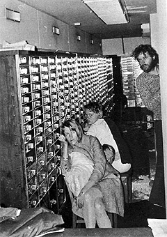 Bankraneren Clark Olofsson til høyre, skuler mot kamera mens to kvinnelige gisler sitter i bankvelvet 23. august 1973. Fotografiet ble tatt med et kamera som ble senket ned i et hull i taket. (Foto: Svensk Politi/AP)
