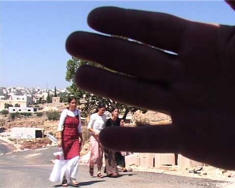 Det bor 450 israelske nybyggere i byen. En av dem forsøkte å hindre NRKs fotograf å filme settlerjenter ved å holde hånden foran bilvinduet.