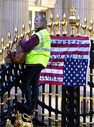 Til tross for de 14.000 politifolkene har det lykkes en demonstrant å klarte helt til topps i porten på Buckingham Palace (Scanpix/AP)