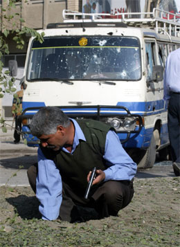 Ein politimann undersøkjer staden der bomba eksploderte. (Foto: AP-Reuters)
