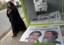 En irakisk kvinne passerer dagens avisforsider i Bagdad med bilde av Saddam før og etter. (Foto: A.Saleh, Reuters)
