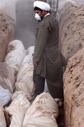 En iransk prest overvåker plasseringen av døde i en av massegravene. Over 20.000 er omkommet, og det fryktes epidemier (Scanpix/AP)