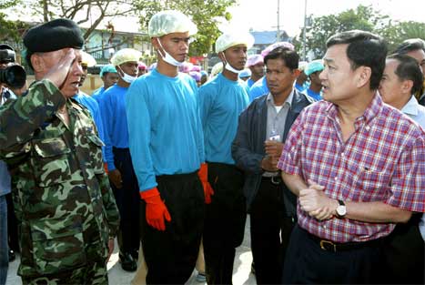 Thailands statsminister Thaksin Shinawatra (t.h.) snakkar med soldatar som er utkommanderte til å slakte kyllingar. (Scanpix/AP-foto)