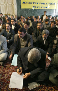 Et medlem av den iranske nasjonalforsamlingen skriver under på sin avskjedsøknad. Foto: AFP/Scanpix 