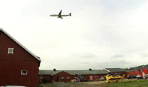 Et fly går inn for landing over en gård i Ullensaker. Foto: NRK.