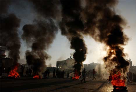 Rasande palestinarar samla seg rundt brennande bildekk i Gaza by. (Foto: AP/Scanpix)