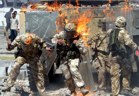Britiske soldater forsøker å riste av seg flammene. (Foto: Reuters/Scanpix)