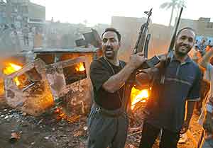 Triumferende militsoldater jublet foran brennende armeikanske kjøretøy i Sadr utenfor Bagdad. (Foto: AFP(