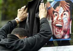 En supporter bøyer seg over et bilde av Maradona utenfor sykehuset i Buenos Aires der han er innlagt. (Foto: Reuters/Scanpix)
