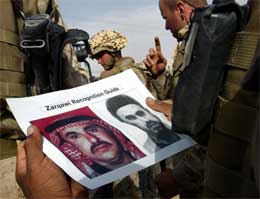 Amerikanske soldater studerer et flygeblad med bilde av Musab al-Zarqawi (Scanpix/AP)