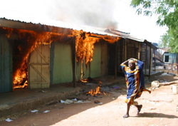Ei jente løper forbi et hus satt i brann av den kristne militsen i Yelwa. (Foto: G.Osodi, AP)