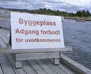 Et skilt forteller om at det ikke er lov å gå på byggeplassen. Likevel bodde det folk i hyttene, og turister gikk rundt og kikket da NRK var der tirsdag. ( Foto: Kathrine Brønn, BRK )