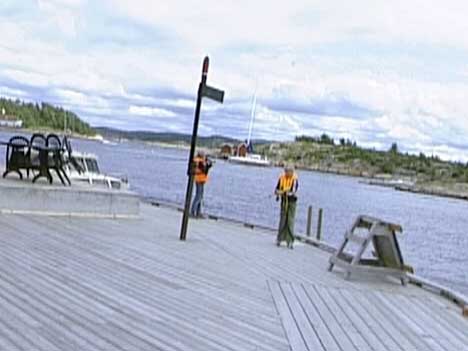 Barna står og fisker på brygga rett bak skiltet der det står adgang forbudt på byggeplassen. ( Foto: Kathrine Brønn, NRK )