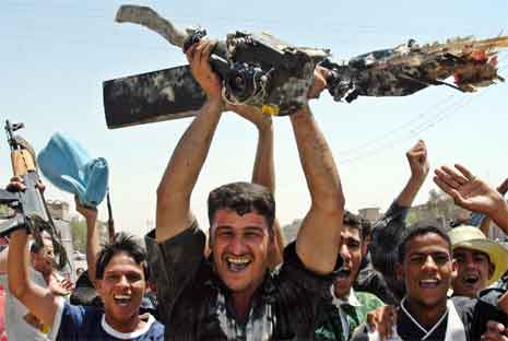 Tilhengere av Muqtada al-Sadr brer triumferende rundt p restene av en rotor fra et nedskutt amerikansk helikopter. (Foto: Reuters/Scanpix)