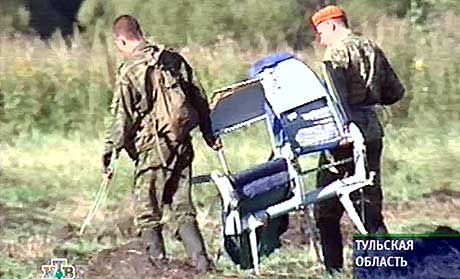 STYRTET: To soldater frakter bort en stol fra flyet som styrtet utenfor Tula, 180 km sør for Moskva. (Foto: AFP/NTV)