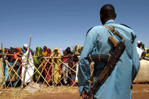 En soldat står vakt mens Darfur-flyktninger får utdelt mat. (Foto: AP)