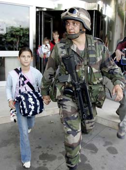 En fransk soldat hånd i hånd med ei jente som evakueres fra et hotell i Abidjan i dag. (Foto: P. Guyot, AFP)