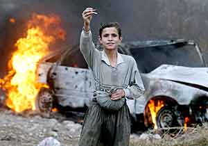 En irakisk gutt viser frem kuler nær en brennende bil i Bagdad fredag. Foto: Ceerwan Aziz , Reuters