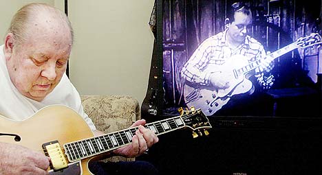 Hank Garland spiller sin gitar i sitt hjem i Orange Park, mens han ser på et videoklipp av seg selv fra 1950-tallet. Foto: Oscar Sosa, AP Photo.