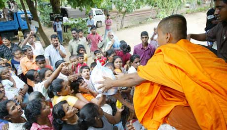 Buddhistmunker deler ut mat til overlevende i Ambalantota. Andre måtte begrave de som mistet livet da toget ble tatt, noe som ifølge BBC gjør episoden til historiens verste togulykke (Foto: Thomas White /Reuters / Scanpix)
