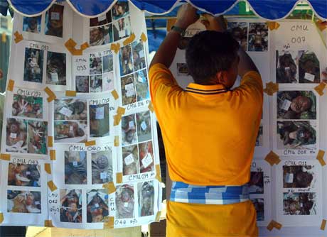 Omfanget av omkomne og savnede er enormt. Her henger en mann opp bilder av savnede i Phang Nga-provinsen sør for Bangkok. (Foto: Reuters/Scanpix)