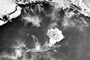 Alliert angrep på det tyske slagskipet "Tirpitz", som står i brann etter et bombetreff. En liten båt fjerner seg raskt fra "Tirpitz". Foto: Scanpix.
