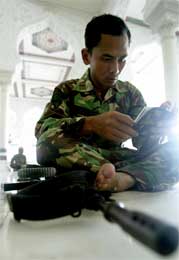 I mange av fredagens bønner ble det nok bedt om fred, men denne soldaten, som leser Koranen, har også geværet sitt med seg (Scanpix/Reuters)