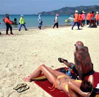 Turister og oppryddningsarbeidere på stranden i Phuket i Thailand. (Foto: Reuters/Scanpix)