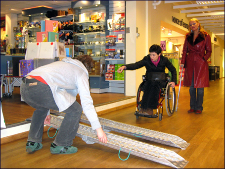 Eilin Reinaas og Tove Hoem i handikapforbundet i Molde må ha hjelp til å få satt opp egen rampe for å komme seg inn i fotobutikken i Moldetorget. Foto: Gunnar Sandvik
