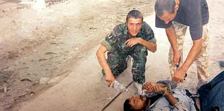 P bildet sees en av de dmte,  Daniel Kenyon, t.h. bye seg over en irakisk fange som ligger nede. (AFP)