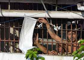 Fanger vifter med hvite flagg gjennom cellevindu. (Foto: Joel Nito, AFP) 