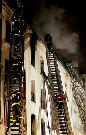 DRAMATISK HOTELLBRANN: Brannmannskapene måtte bruke høye stiger for å nå toppen av hotellet i sentrum av Paris.(Foto: Scanpix / AFP PHOTO / Paschal Pavani)