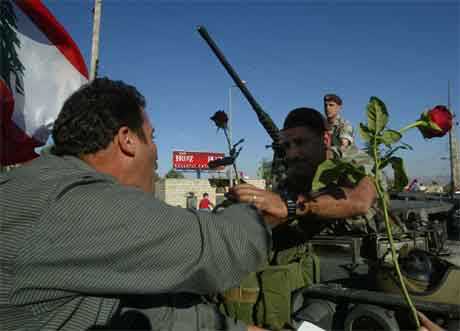 Ein mann gir blomar til ein libanesisk soldat som har innteke det tidlegare hovudkvarteret til den syriske etterretninga i Libanon. (Foto: AP/Scanpix)